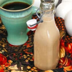 a small batch of pumpkin spice creamer next to a cup of coffee.