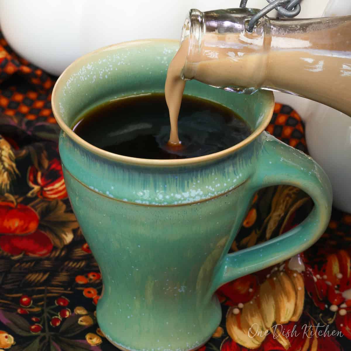 pouring pumpkin spice creamer into a cup of coffee.