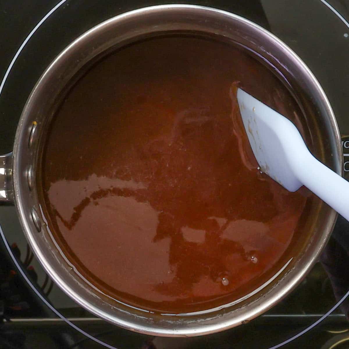 homemade butter pecan syrup simmering in a small pot.