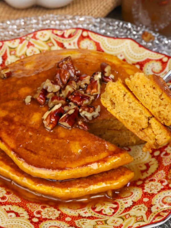 a small batch of pumpkin pancakes topped with syrup on a plate.