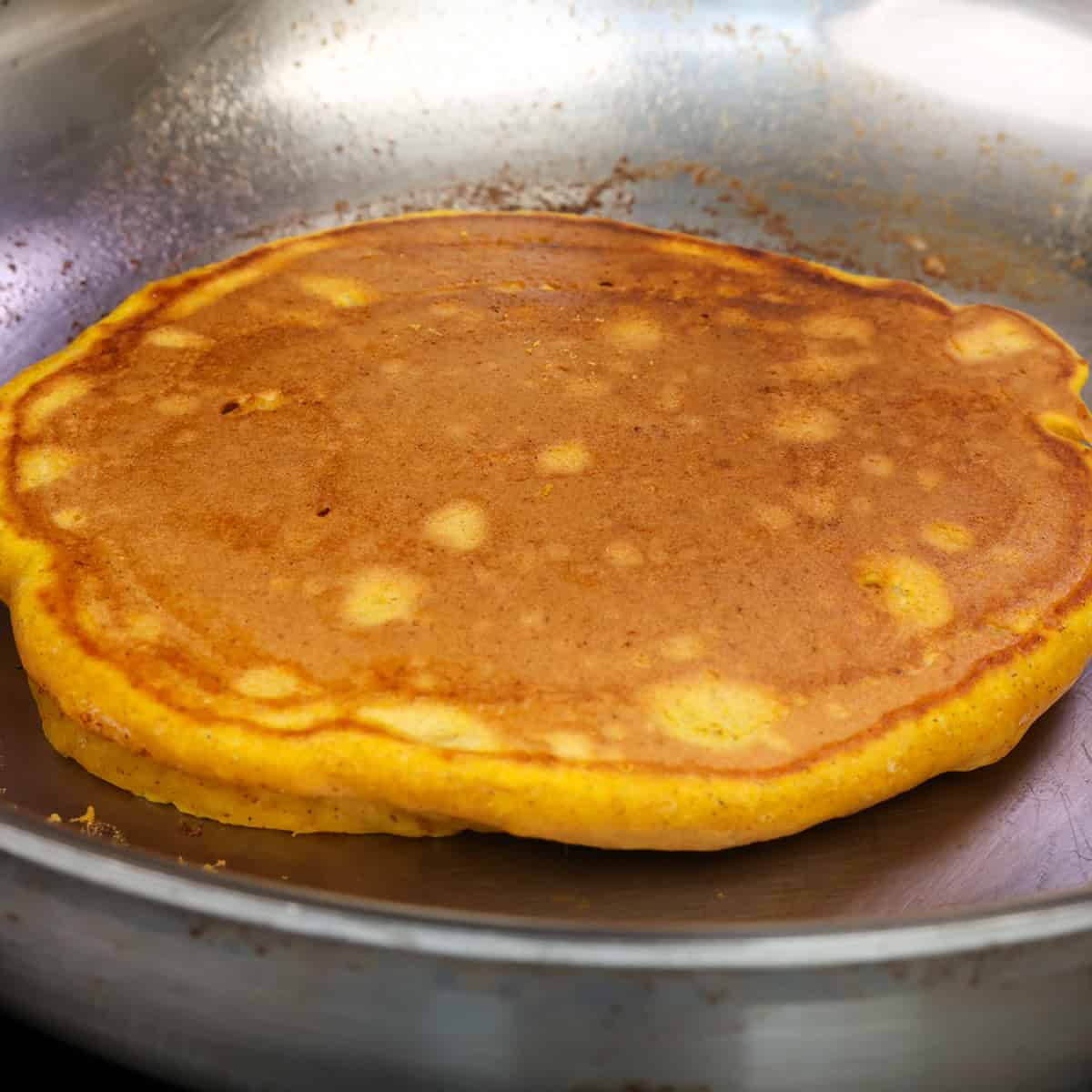 one fluffy pumpkin pancake in a skillet.