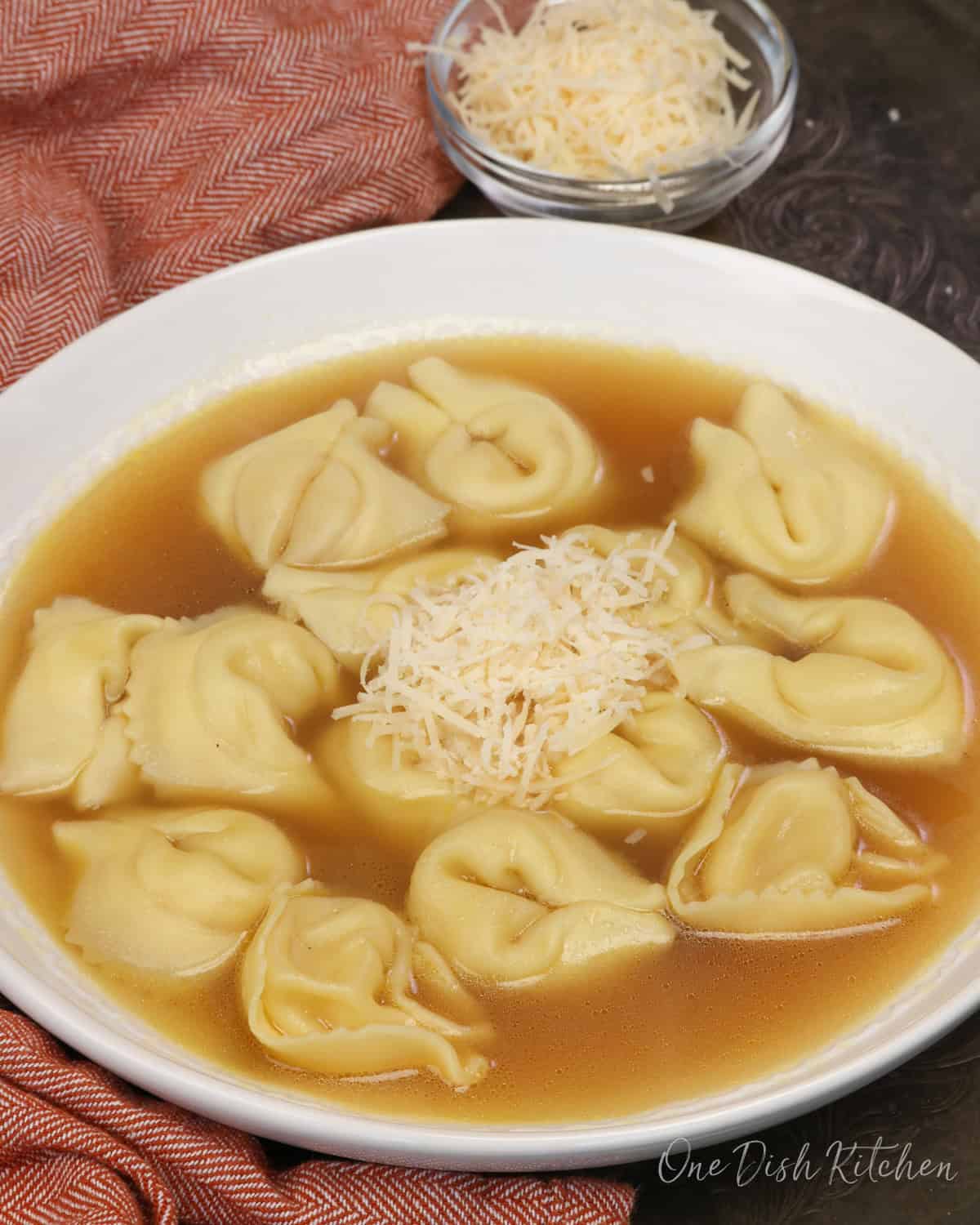 A bowl of tortellini en brodo with cheese tortellini in clear chicken broth.