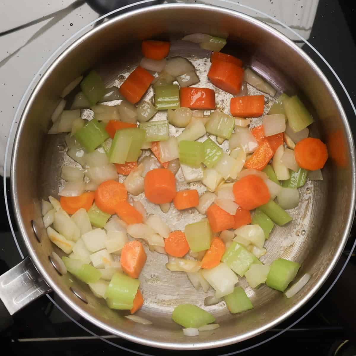 the borscht base of onions, carrots, celery, and garlic cooking in a pot.