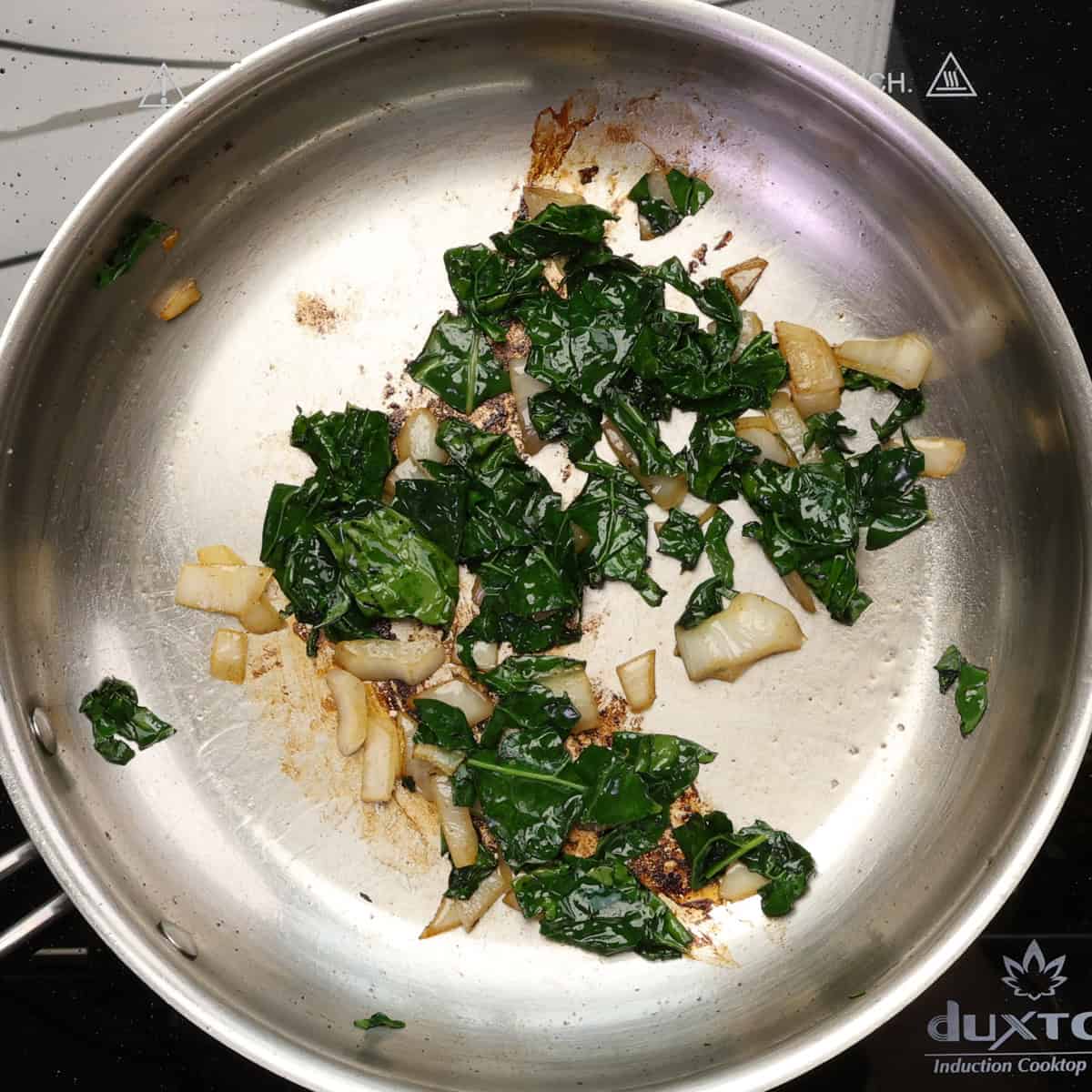 kale and onions cooking in a skillet.