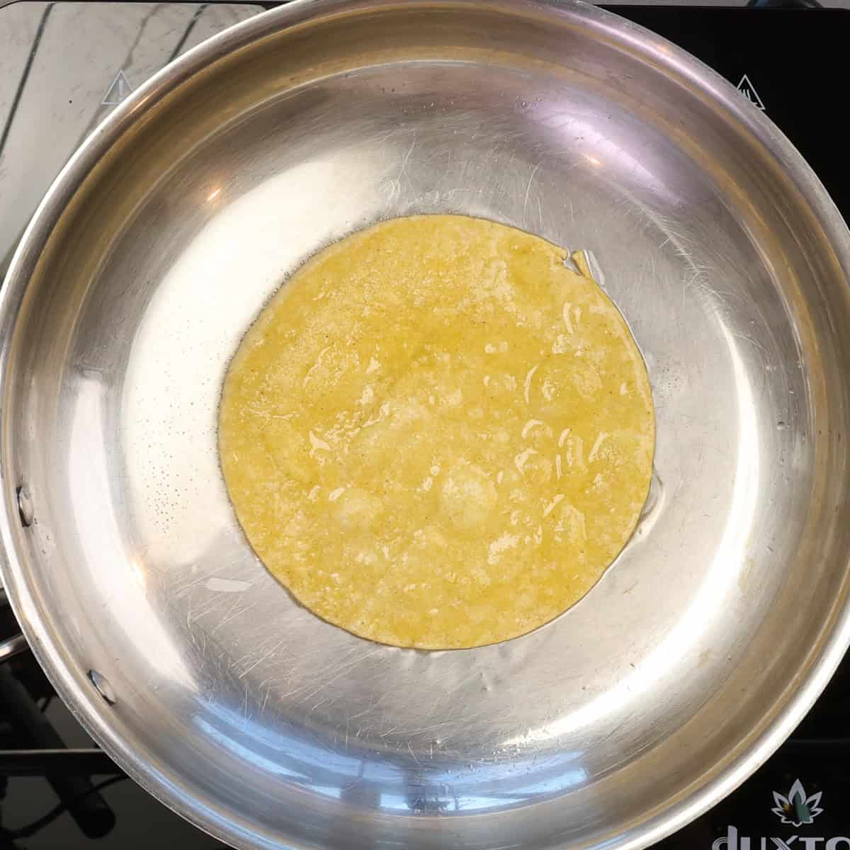 corn tortillas for a texas chicken casserole warming in a skillet.