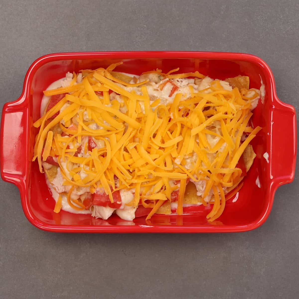 the first layer of a king ranch chicken casserole in a baking dish.