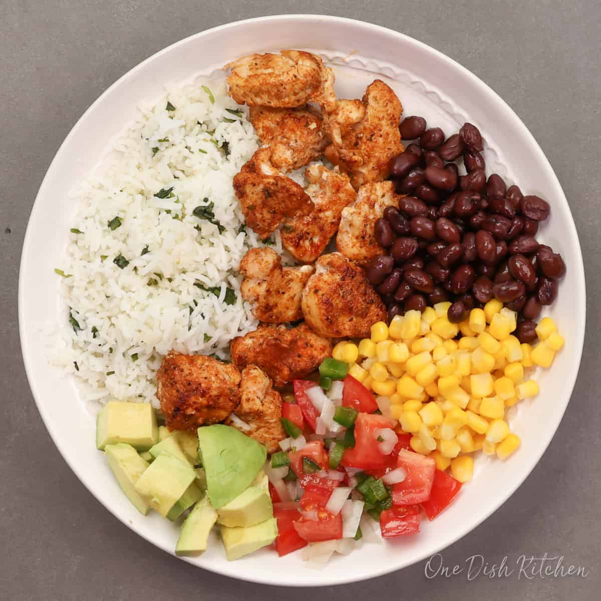 a single chicken burrito bowl with seasoned chicken, rice, black beans, corn, and avocado.