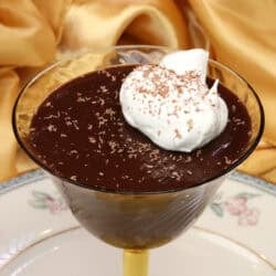 Chocolate pot de crème for one served in a dessert dish topped with whipped cream.