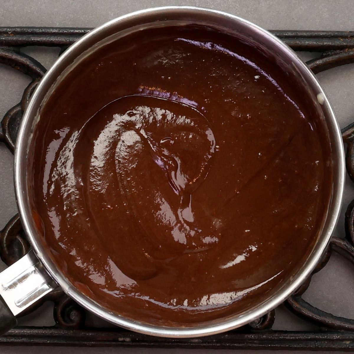 chopped chocolate melting into hot custard in a saucepan.