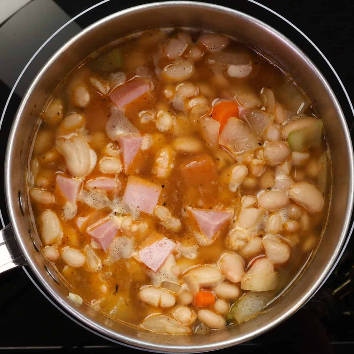 a small batch of ham and bean soup simmering in a pot.
