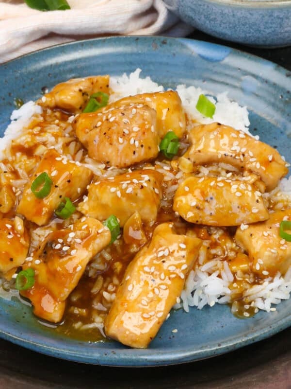 single serving orange chicken over white rice on a blue plate.