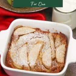 a single serving pear clafoutis in a small baking dish next to a bowl of pears.