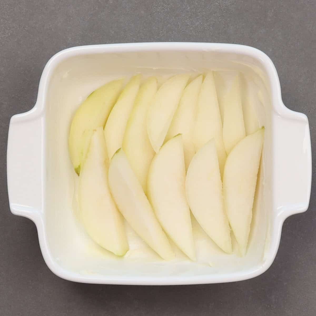 slices of pear lining the bottom of a small baking dish.