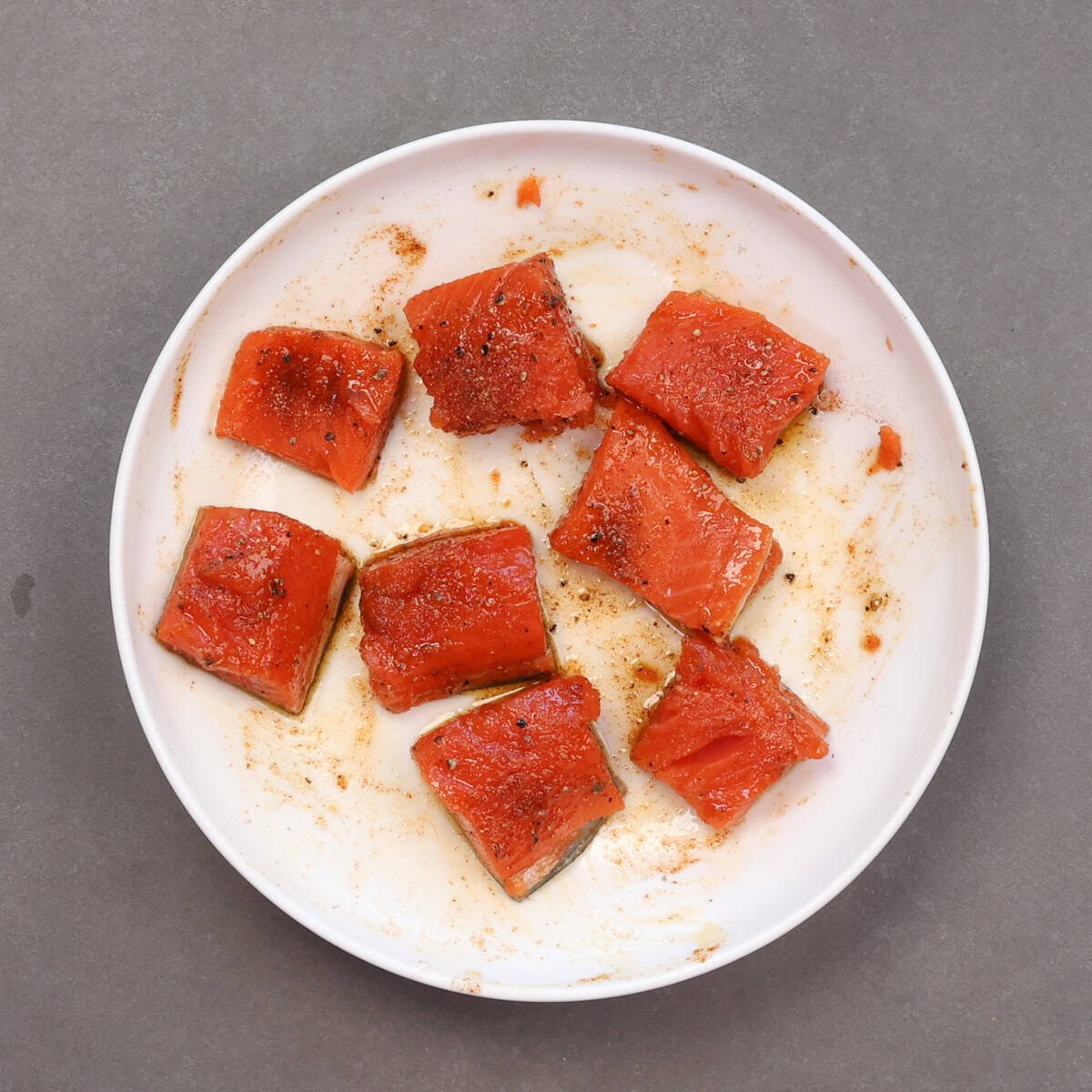 uncooked seasoned cubes of salmon on a plate.