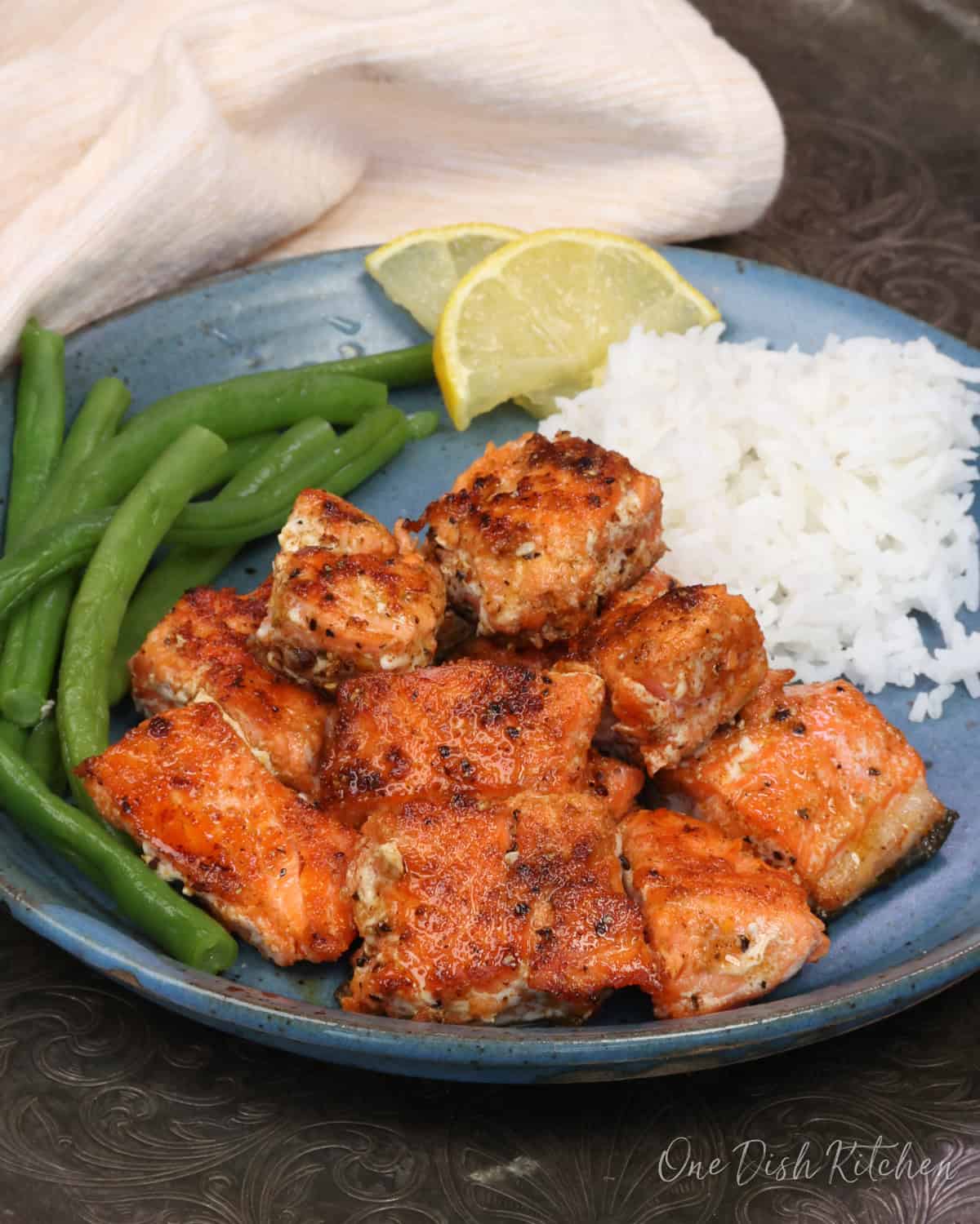 Oven baked salmon bites on a plate, seasoned and cooked until flaky.
