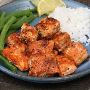 Oven baked salmon bites on a plate, seasoned and cooked until flaky.
