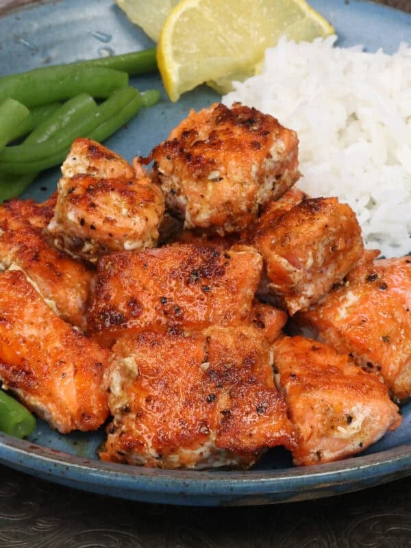 Oven baked salmon bites on a plate, seasoned and cooked until flaky.