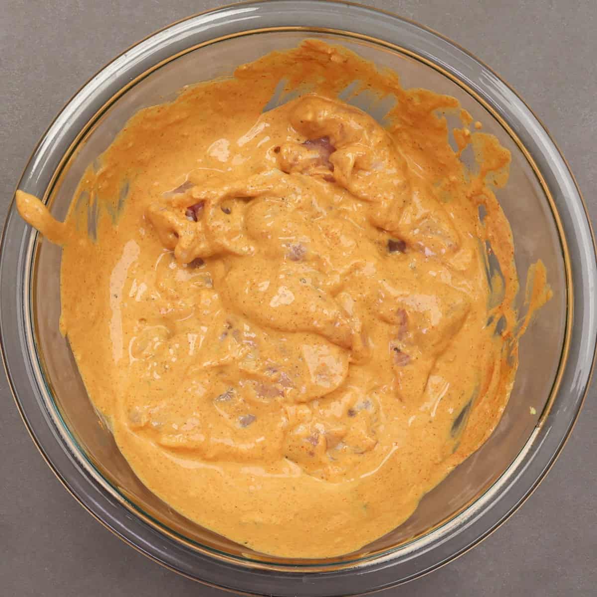 two chicken thighs marinating in tandoori chicken marinade.