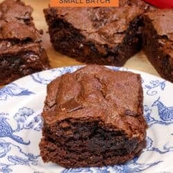 a single flourless brownie on a plate next to three flourless chocolate brownies and a red napkin.