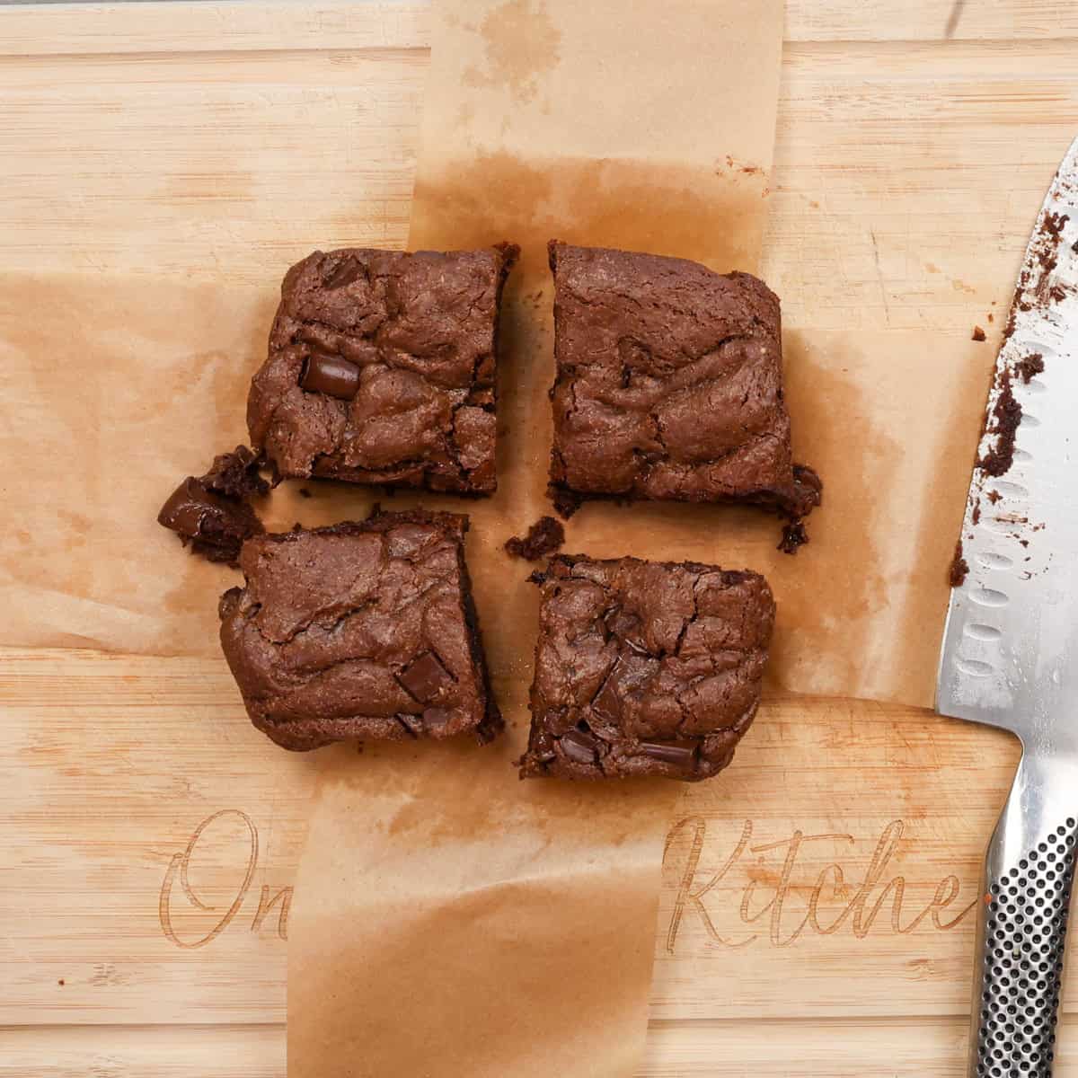 four fudge brownies on a cutting board.